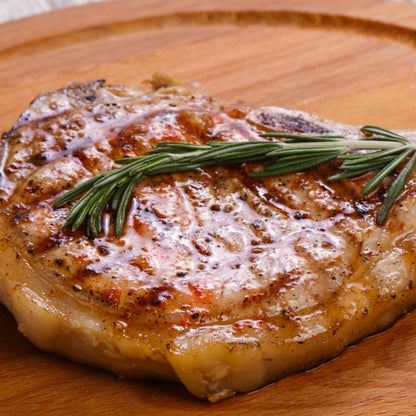 Cooked bacon chops from Primrose Herd, 500g package, showing crispy, savory bacon slices on a white plate.