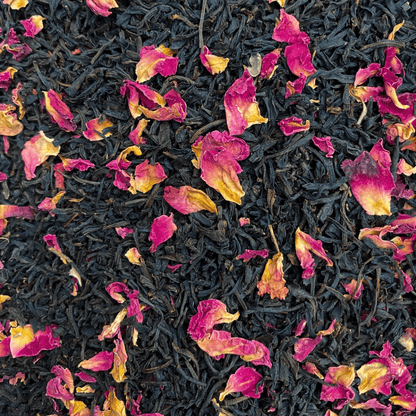 A box of Porter Hill Tea Company's Keemun Rose black tea with loose tea leaves and rose petals on a rustic wooden surface.