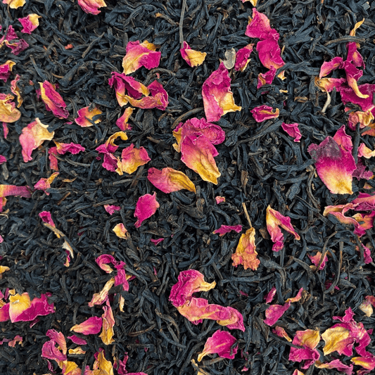 A box of Porter Hill Tea Company's Keemun Rose black tea with loose tea leaves and rose petals on a rustic wooden surface.