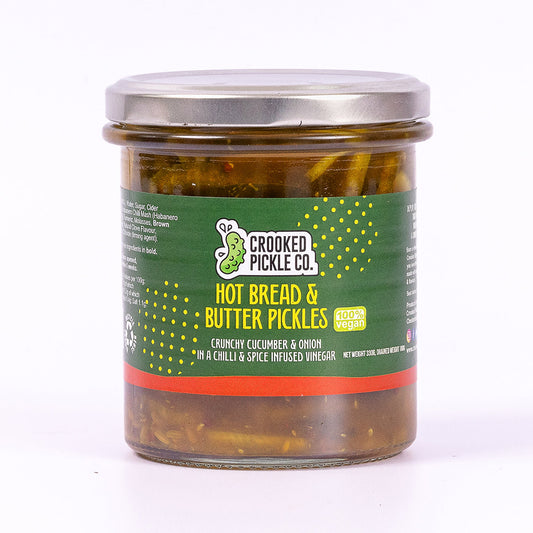 Jar of CROOKED PICKLE CO hot bread and butter pickles with sliced cucumbers visible inside the glass jar.