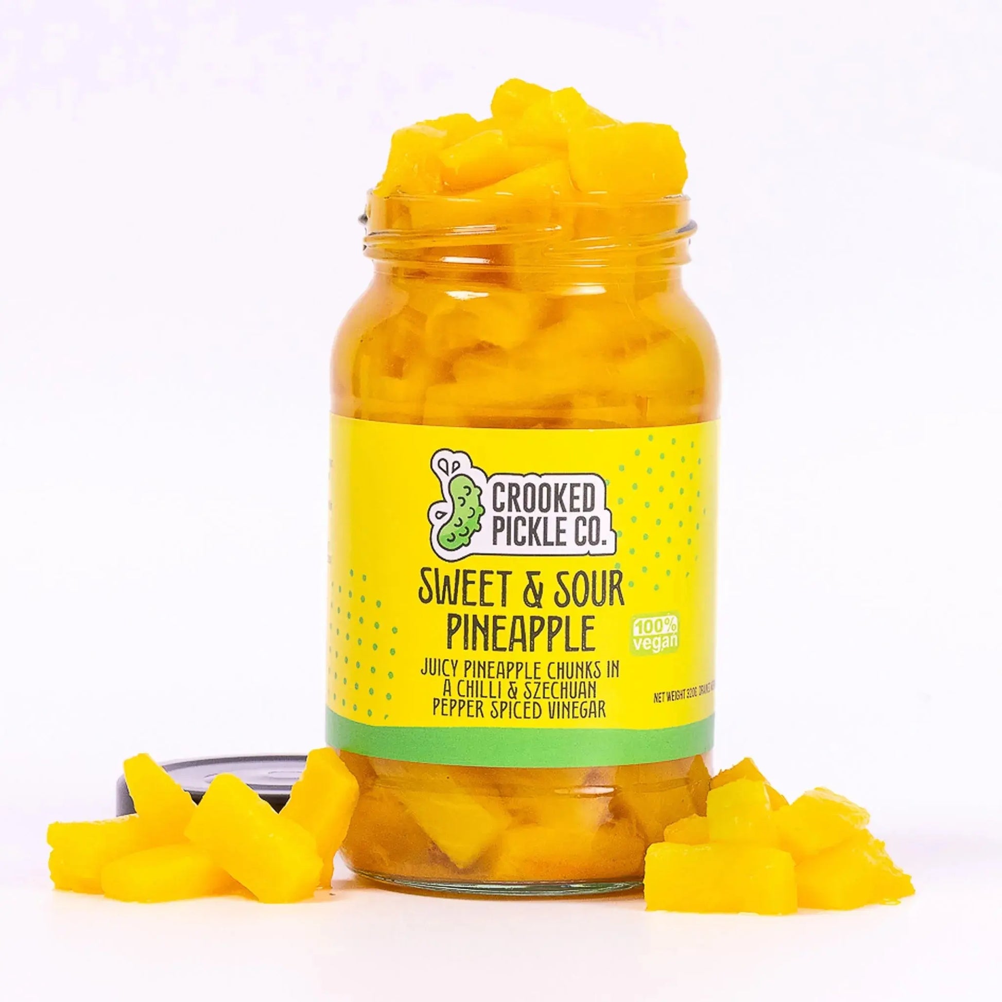Sweet and sour pineapple by Crooked Pickle Co, showing glossy pineapple chunks in a clear jar on a white background.