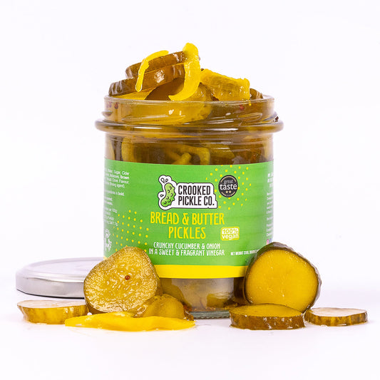 Jar of Crooked Pickle Co. bread and butter pickles with sliced cucumbers and briny liquid in a clear glass jar.