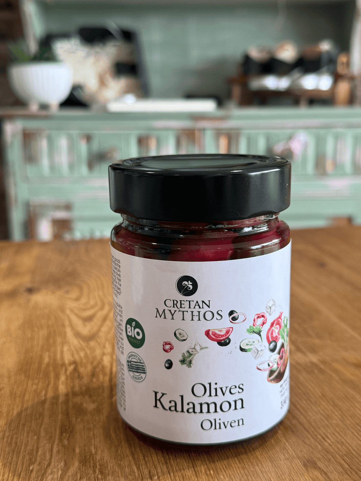 Greek organic Kalamata olives in brine from Cretan Mythos, displayed in a glass jar with olives and brine visible.