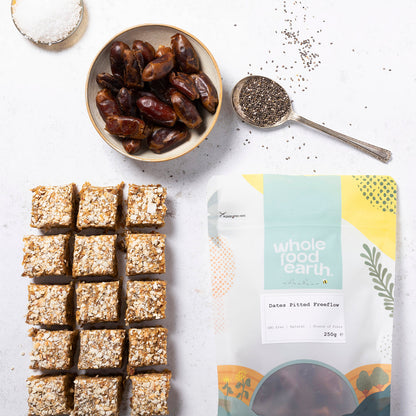 Piles of pitted dried dates from Whole Food Earth in a freeflow container, showcasing their rich, natural brown color and smooth texture.
