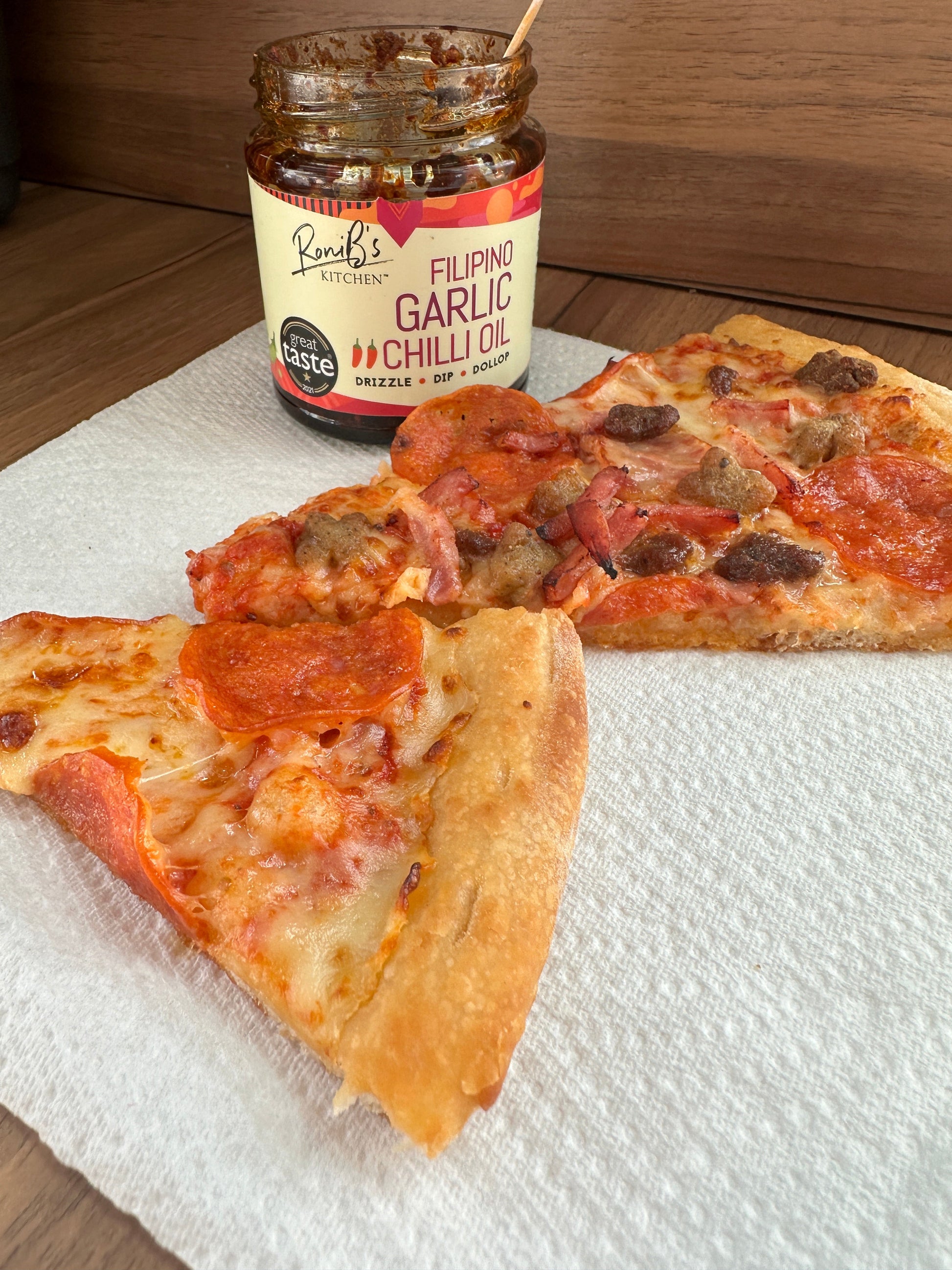 Filipino style garlic chili hot sauce by RoniBs Kitchen drizzled over a pizza, showcasing its vibrant red color and spicy flavor.