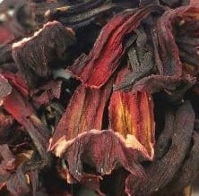 Bright red hibiscus flower and leaves in a cup of Porter Hill Tea Company hibiscus fruit and herbal tea.