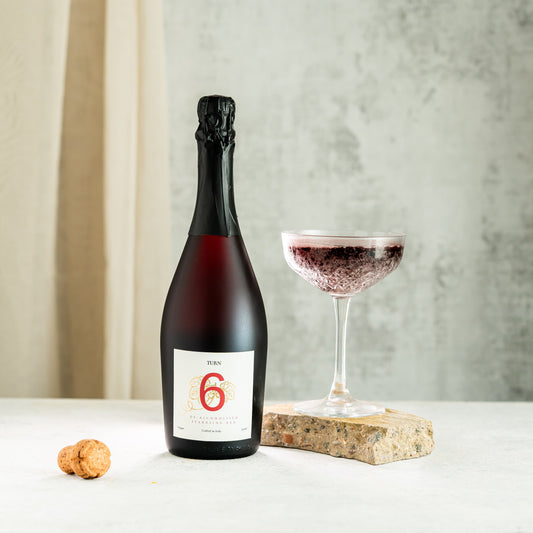 Glass of alcohol-free sparkling red wine from Turn 6, showcasing vibrant red color and sparkling bubbles in a high-resolution image.