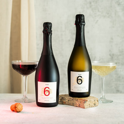 Six-pack of Turn 6 premium alcohol-free sparkling white and red wine bottles with elegant labels on high-resolution image.