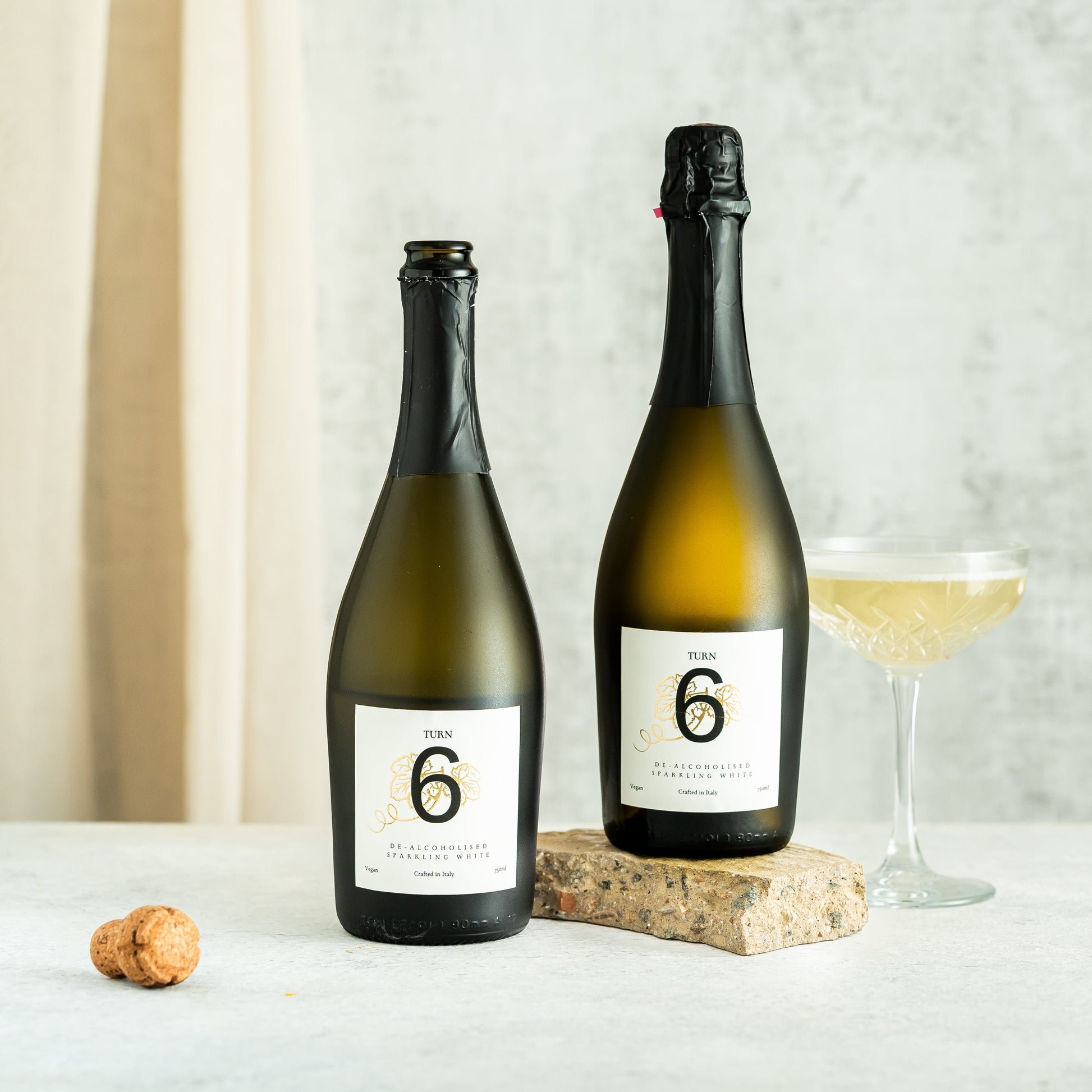 Six bottles of Turn 6 premium alcohol-free sparkling white wine in a case, showing clear glass bottles with white wine and foil caps.