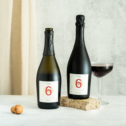 Six bottles of Turn 6 premium alcohol-free sparkling red wine in a case, showcasing vibrant red wine and elegant glassware.