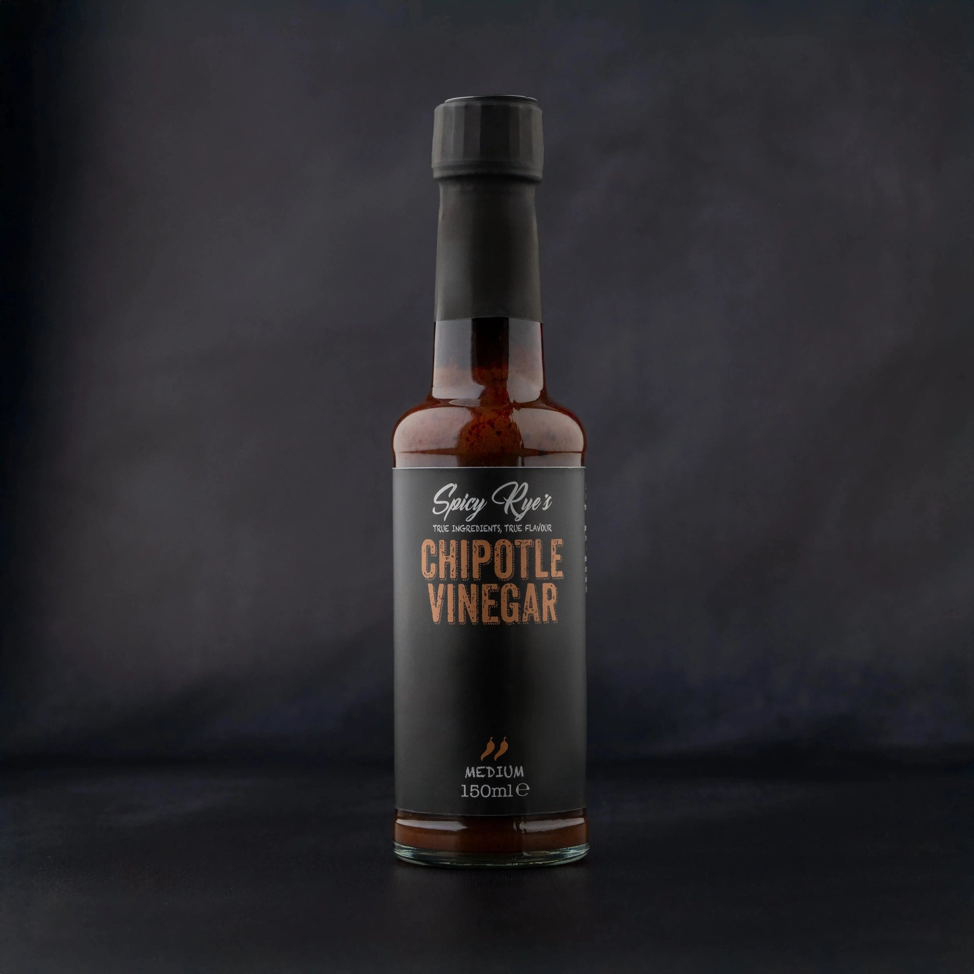 Spicy Ryes Chipotle Vinegar bottle with dark liquid inside, featuring a label with chipotle peppers and branding.