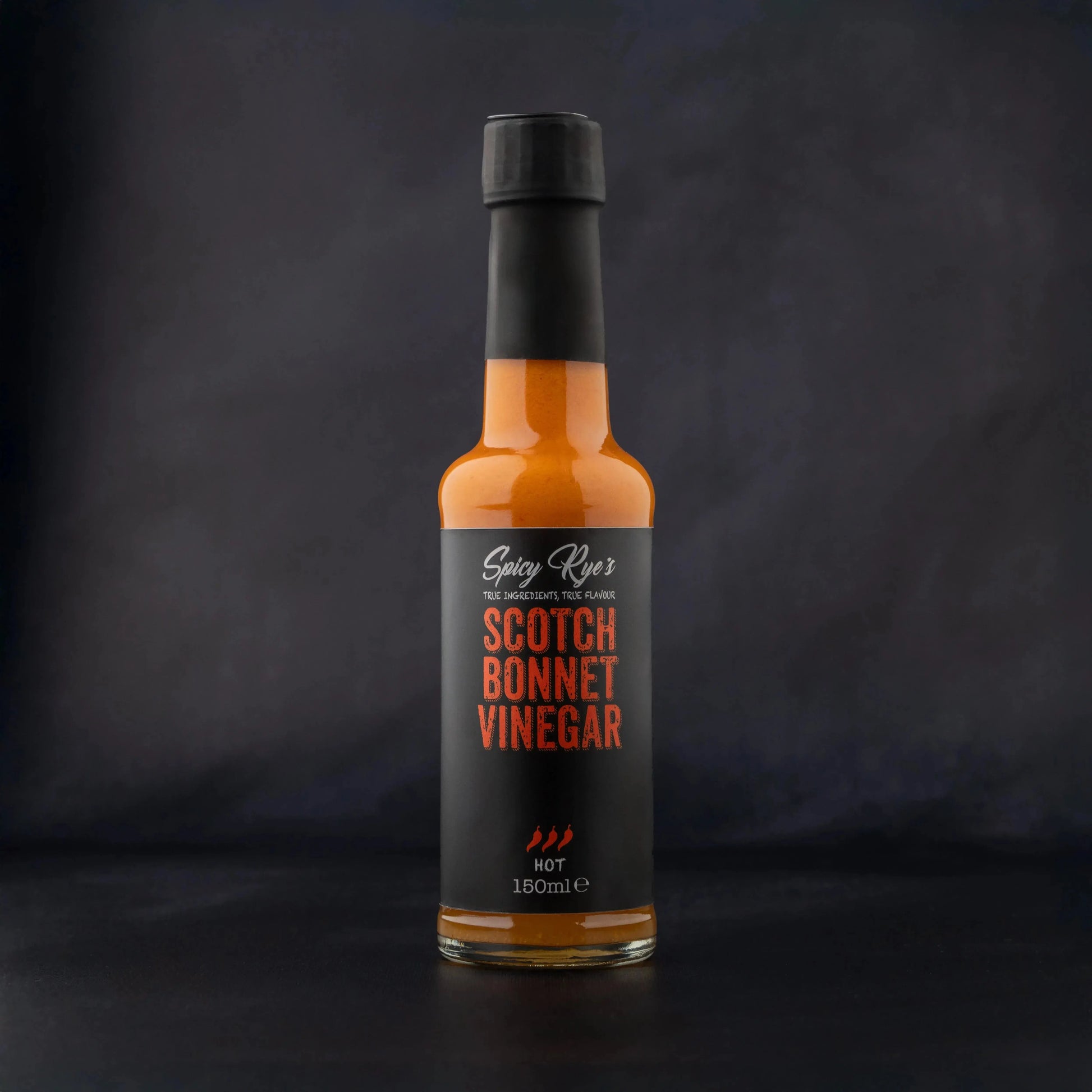 Spicy Ryes Scotch Bonnet Vinegar bottle with label, showcasing bright red chili peppers and bold branding on a white background.