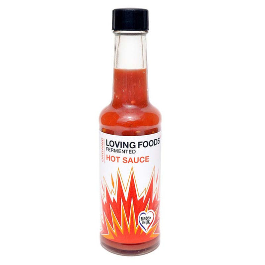 Bottle of Loving Foods organic hot sauce with red chili peppers and fresh ingredients in a clear glass container.