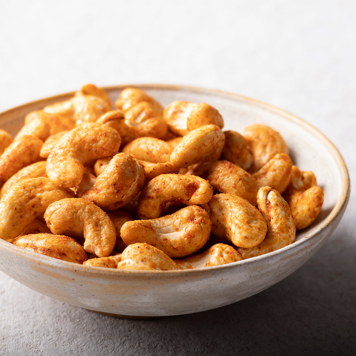 Spicy hot chili baked cashews from Whole Food Earth in a bowl, showcasing roasted nuts coated with chili seasoning.