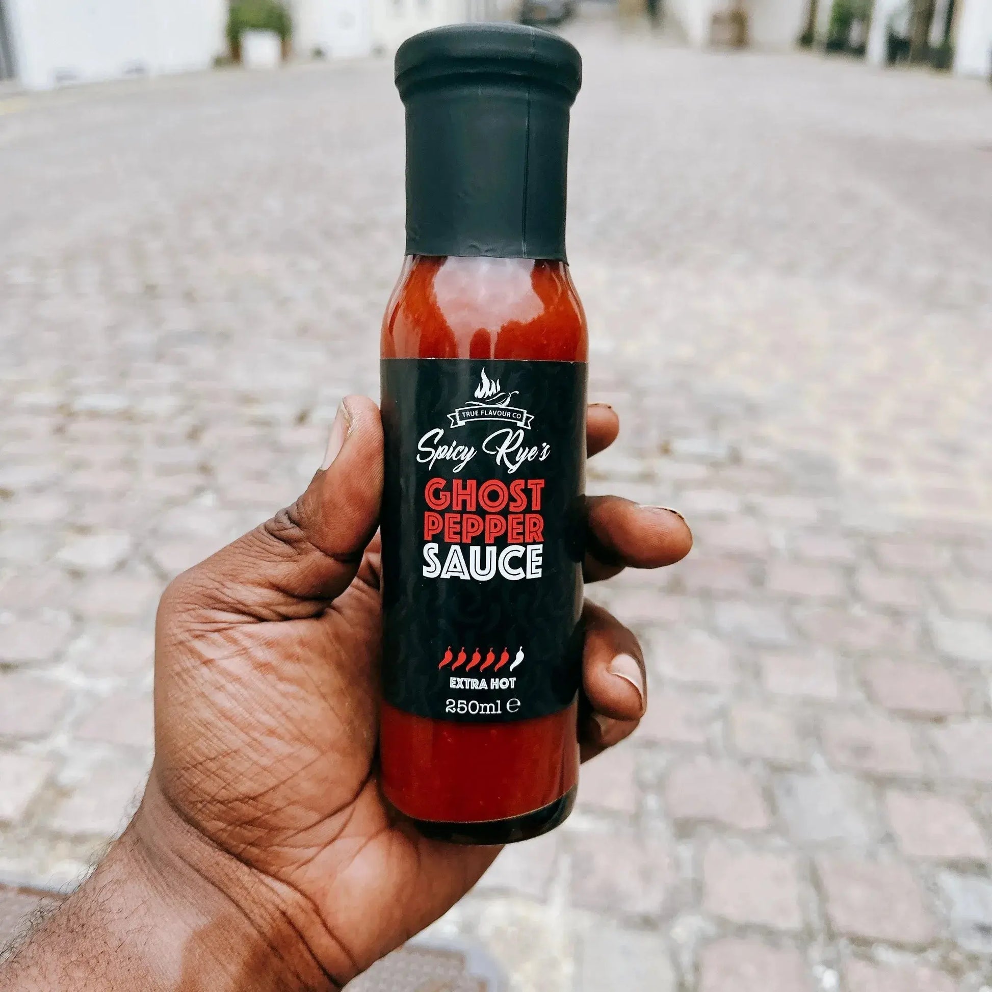 Spicy Ryes Ghost Pepper Hot Sauce in a glass bottle with a fiery red label, showcasing the intense chili peppers inside.