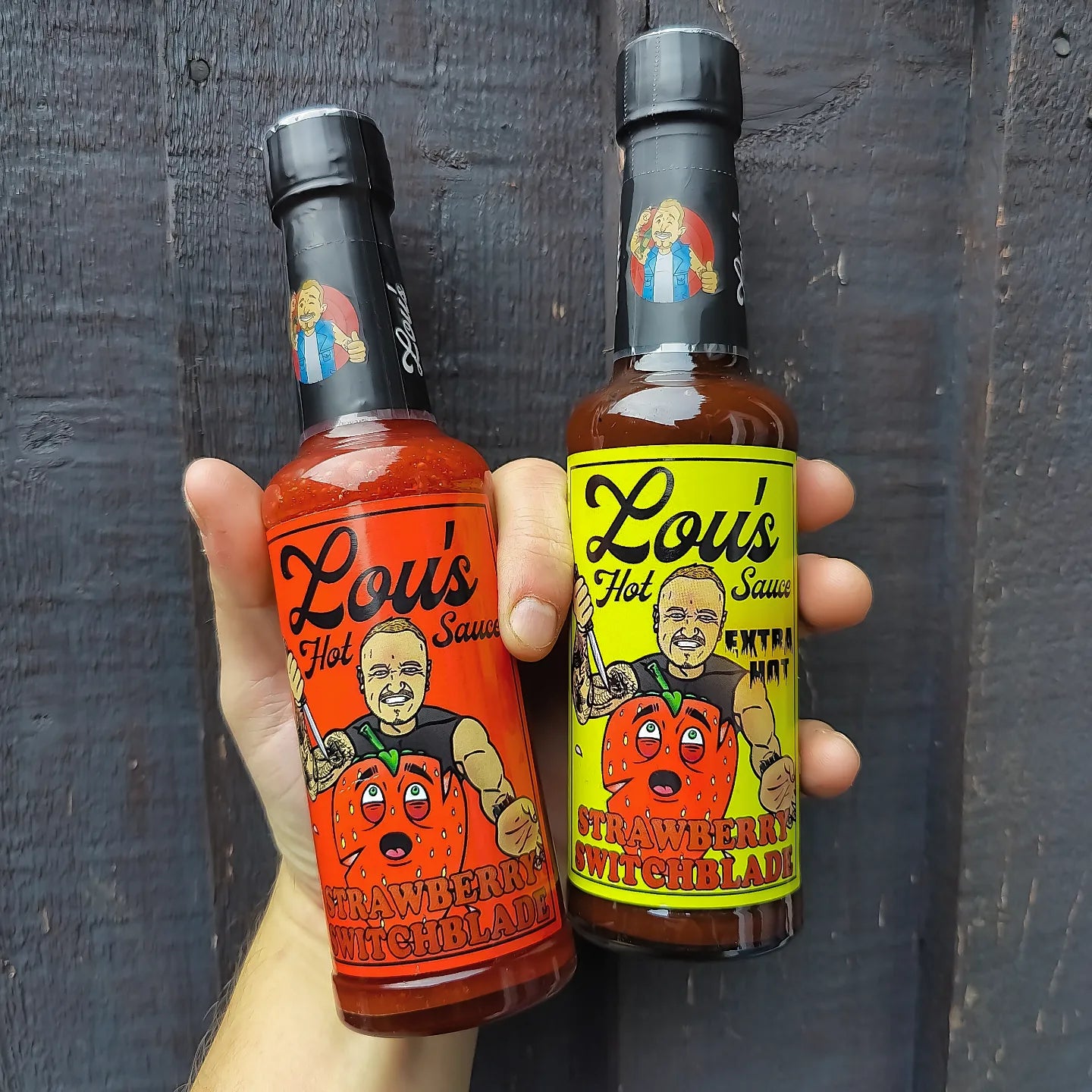 Strawberry Switchblade Carolina Reaper hot sauce in a glass bottle, featuring bright red sauce with fresh strawberries and peppers.