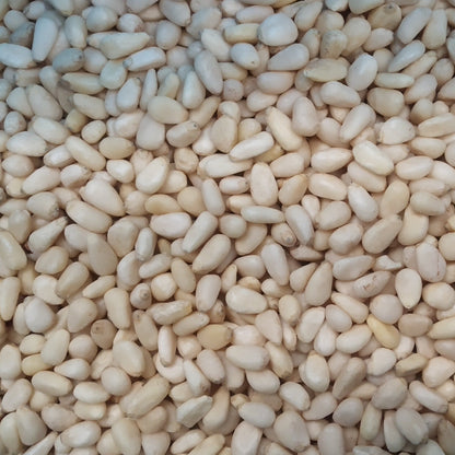 Whole Food Earth pine nuts in a clear bowl, showing their small, creamy beige seeds from the Nuts & Seeds category.