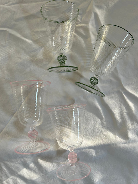 Two pink Dido Venetian wine glasses with elegant stems and clear bowls, set against a neutral background.