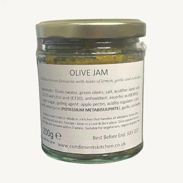 Jar of The Condiments Kitchen Olive Jam chutney with green olives and herbs, 195g, on a wooden surface.