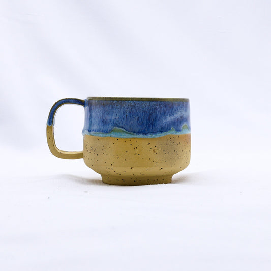 Sienna handmade ceramic mug by Ribera Handmade Ceramics with a textured glaze and organic shape on a wooden surface.