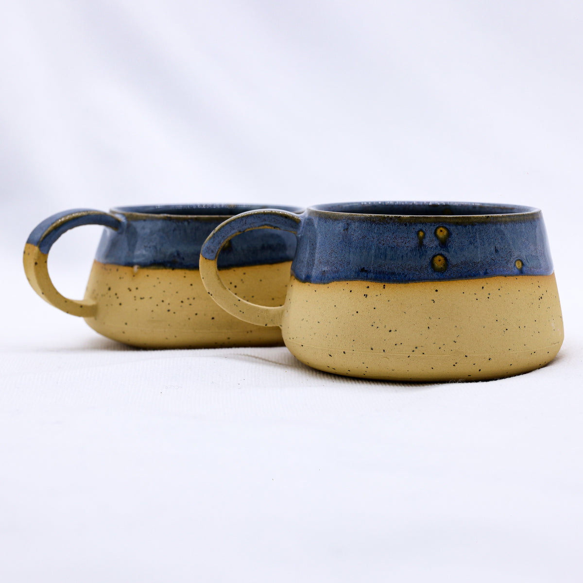 Blue and earthy-toned Bluvio Belluma handmade stoneware ceramic mug by Ribera Handmade Ceramics, showcasing its textured surface and unique shape.