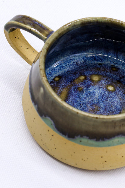 Handmade stoneware ceramic mug by Ribera Handmade Ceramics with a rustic glaze, featuring a rounded shape and textured surface.