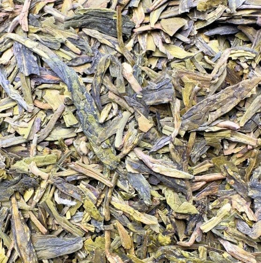 Organic Dragonwell green tea leaves from Porter Hill Tea Company, displayed in a clear glass teacup with fresh, vibrant leaves.