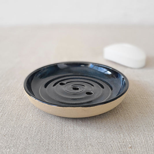 Jet black ceramic soap dish by Katie L Thompson Designs with a bar of soap, sleek and minimalist bathroom accessory.