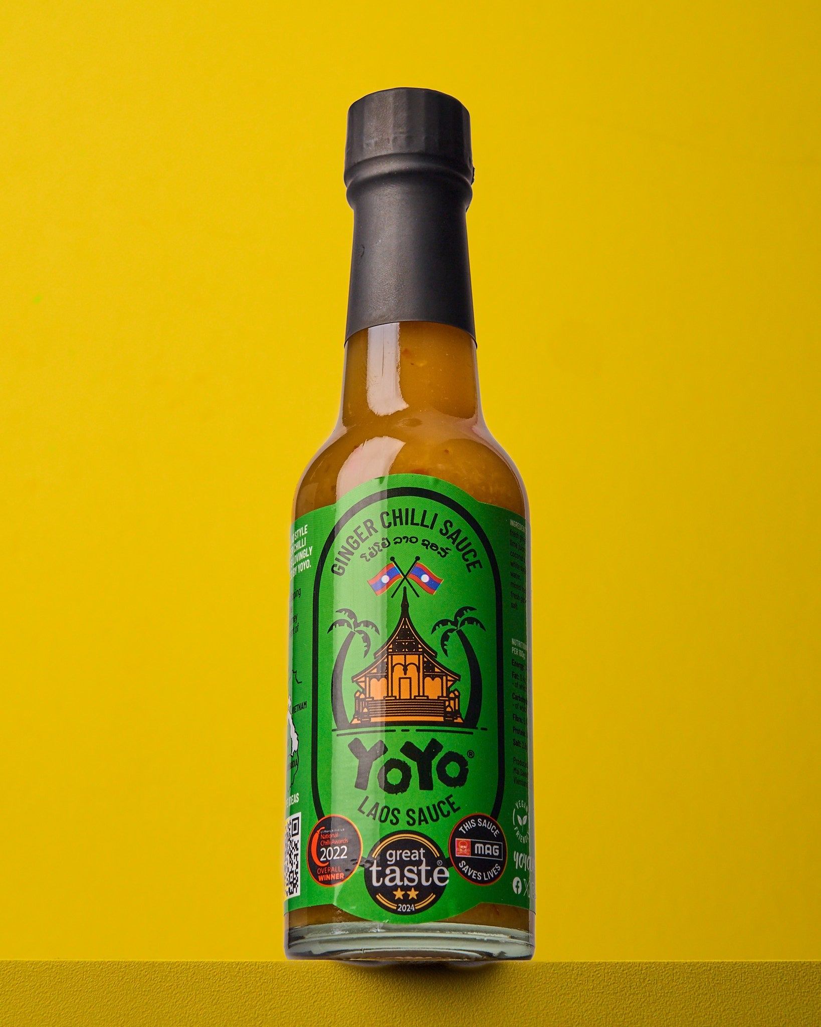 Bottle of YoYo Laos Signature Ginger Chilli Sauce with fresh ginger and red chillies, showcasing the spicy, flavorful sauce.