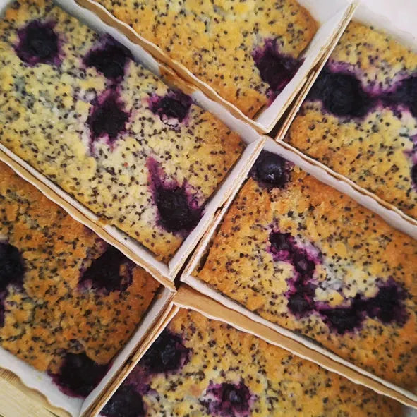 Slices of Lemon, Poppy Seed, and Blueberry Free From Cake by The Healthy Cake Company showing a moist, colorful cake with fresh fruit topping.