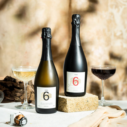 Six-pack of Turn 6 alcohol-free sparkling white and red wine bottles with vibrant labels and elegant packaging.