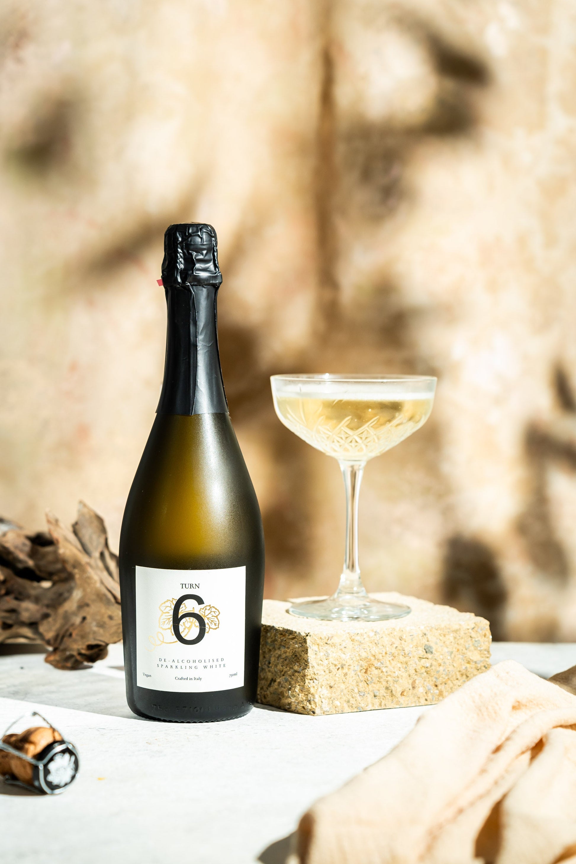Six bottles of Turn 6 alcohol-free sparkling white wine, showcasing clear glass bottles with elegant white wine inside.