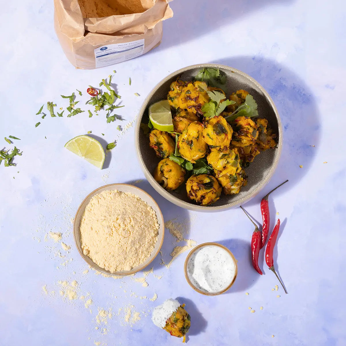Organic maize flour by Whole Food Earth, shown in a kitchen setting with a bowl of fresh maize and a bag of maize flour.
