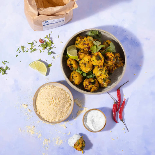 Organic maize flour by Whole Food Earth, shown in a kitchen setting with a bowl of fresh maize and a bag of maize flour.