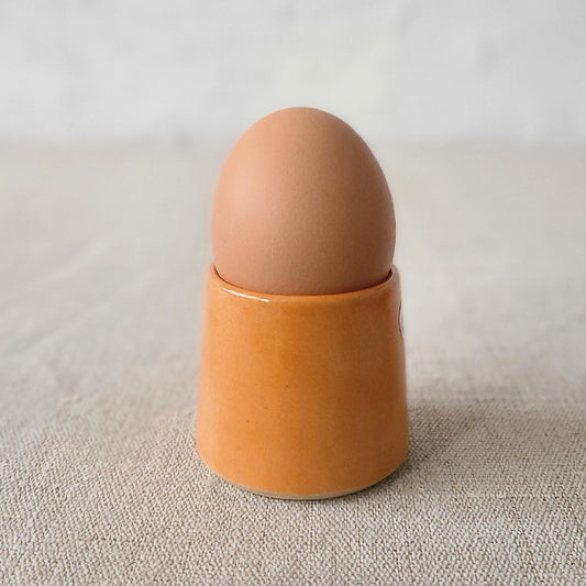 Mandarin orange ceramic egg cup by Katie L Thompson Designs, showcasing a classic egg holder with vibrant orange color.