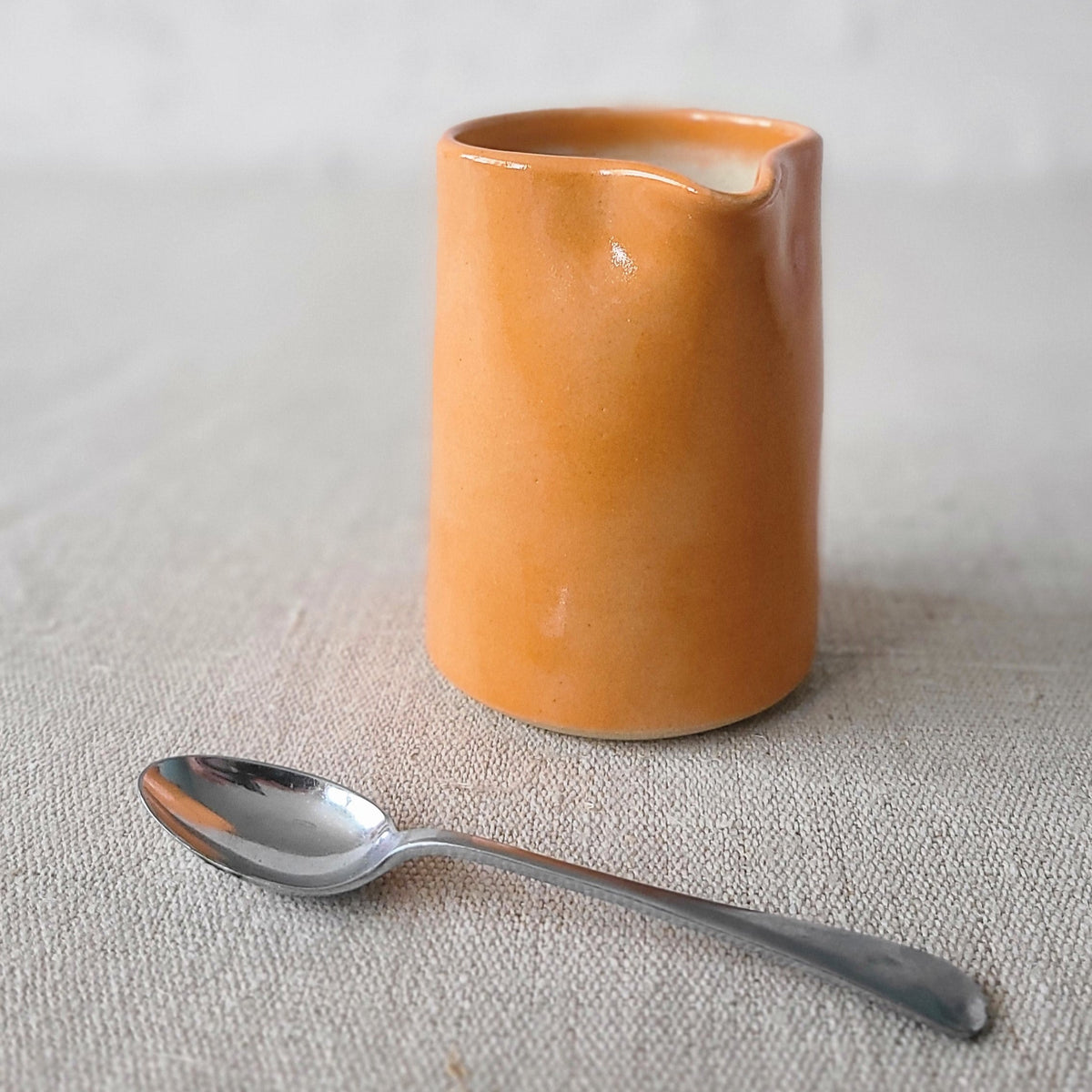 Small ceramic mandarin orange jug by Katie L Thompson Designs with a classic shape and vibrant orange color.