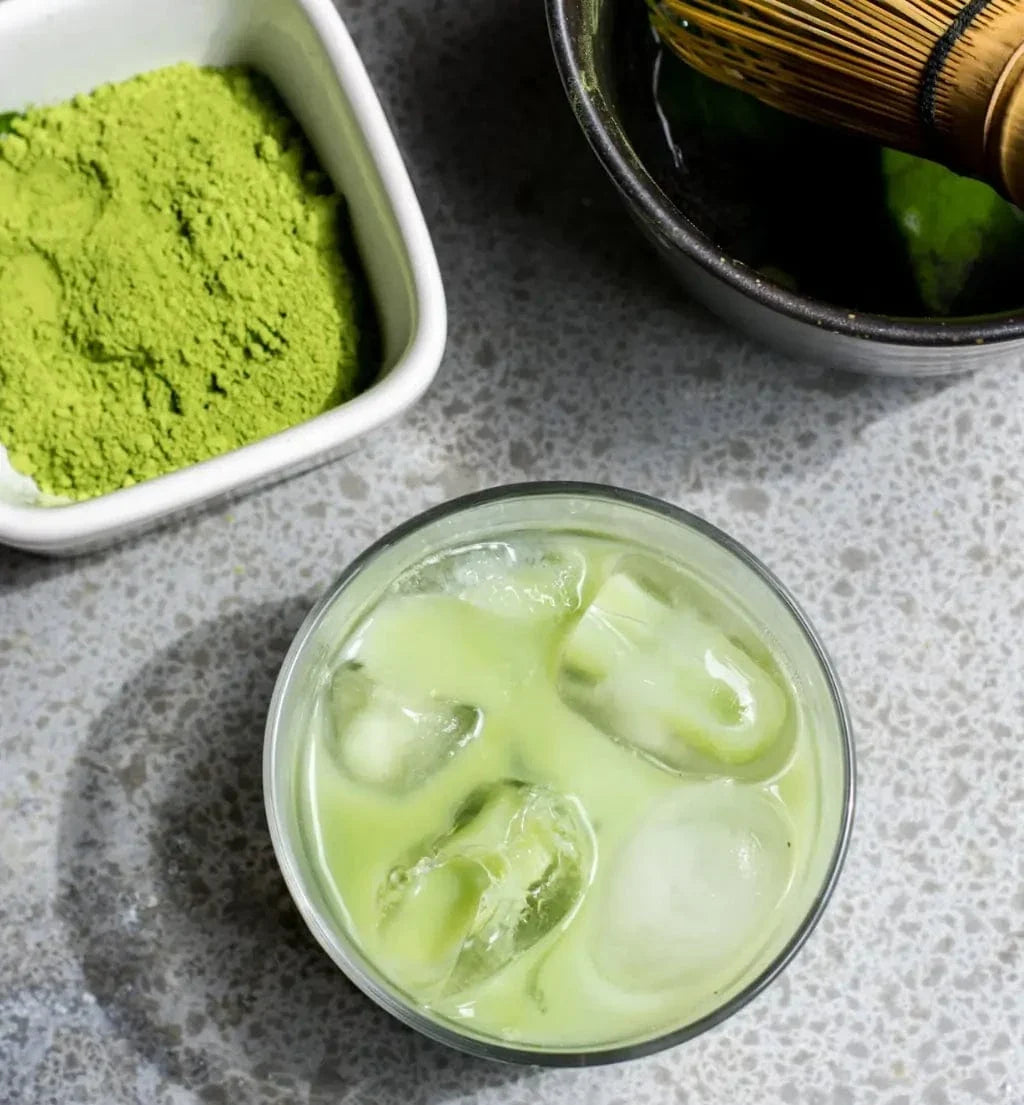 Porter Hill Tea Company's Izu Matcha green tea in a cocktail glass with vibrant green matcha powder and tea leaves.