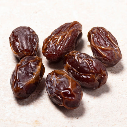 Medjoul dates, Whole Food Earth dried fruit, showing large, glossy, sweet Medjool dates with textured skin in a close-up image.