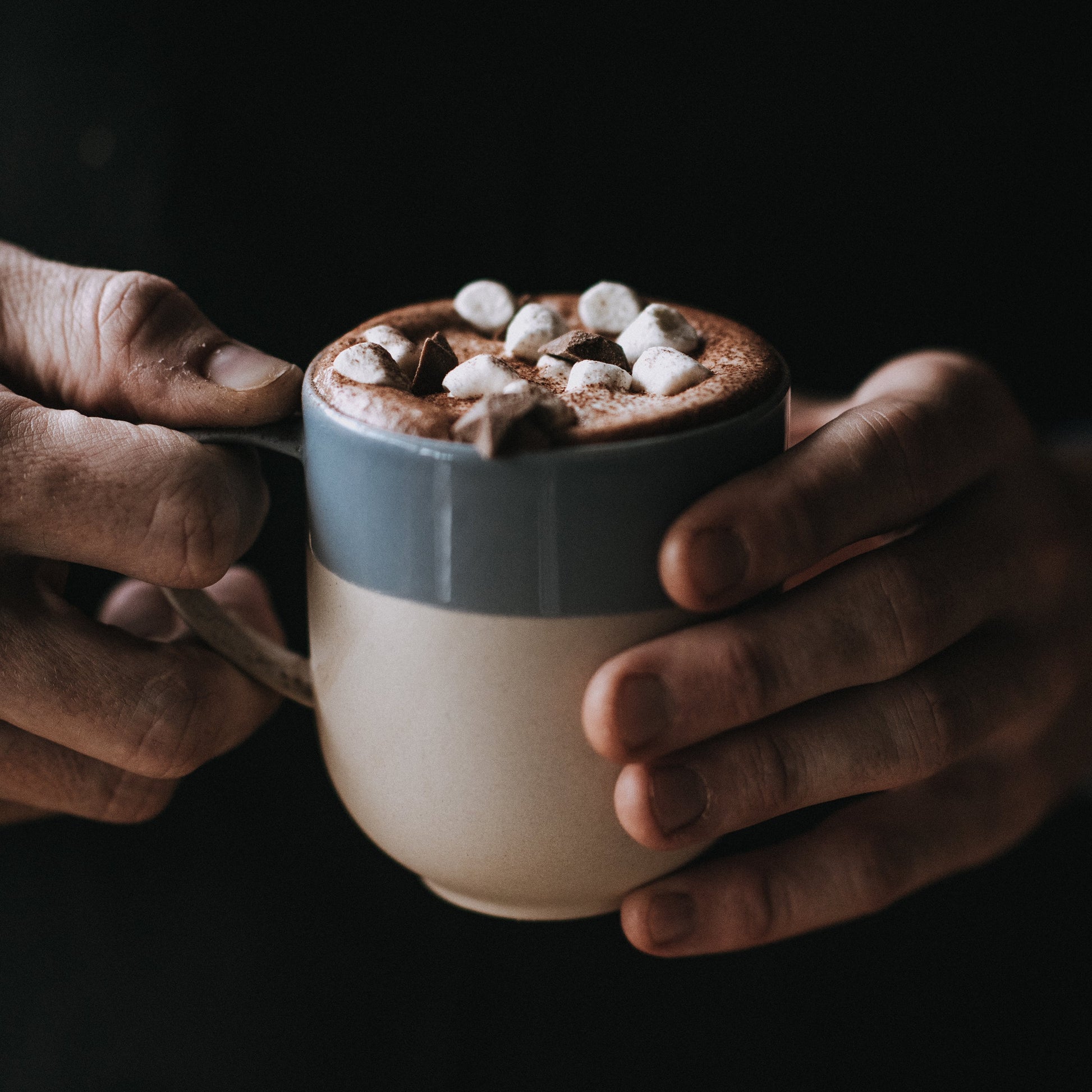 A mug of Harry's Hot Chocolate with 44% dark hot chocolate topped with whipped cream and chocolate shavings.