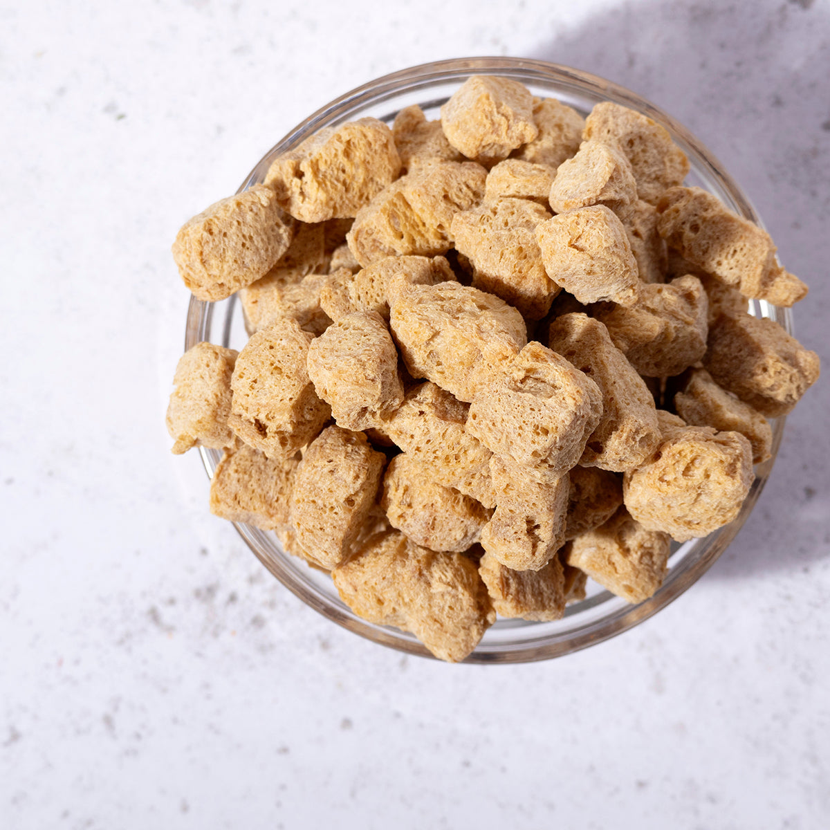 Whole Food Earth TVP natural soy protein chunks in a clear bowl, showcasing their textured, beige soy-based beans and pulses.