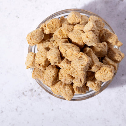 Whole Food Earth TVP natural soy protein chunks in a clear bowl, showcasing their textured, beige soy-based beans and pulses.