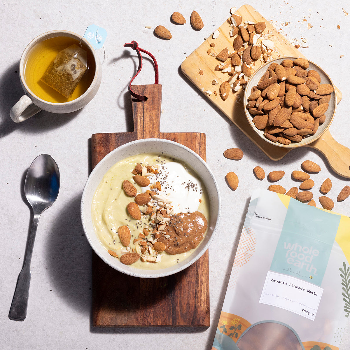 A bowl of organic whole almonds from Whole Food Earth, showing light brown, textured nuts on a rustic wooden surface.