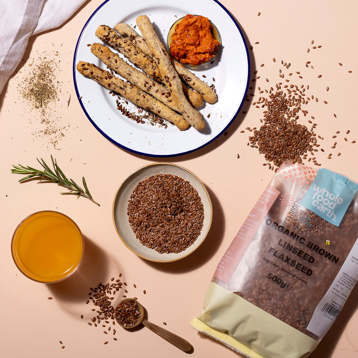Organic brown flaxseed from Whole Food Earth, displayed in a bowl with scattered seeds on a rustic wooden surface.