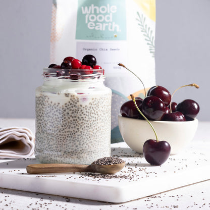 Organic chia seeds from Whole Food Earth in a glass bowl with a spoon, showcasing the nutty seeds on a wooden surface.