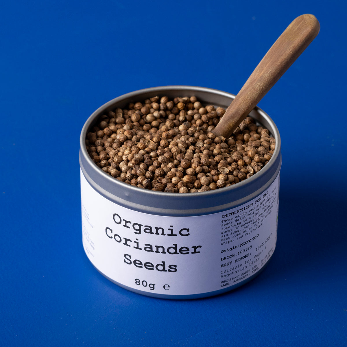 Organic coriander seeds from Whole Food Earth, wild-harvested herbs and spices in a 80g package, with whole seeds visible.