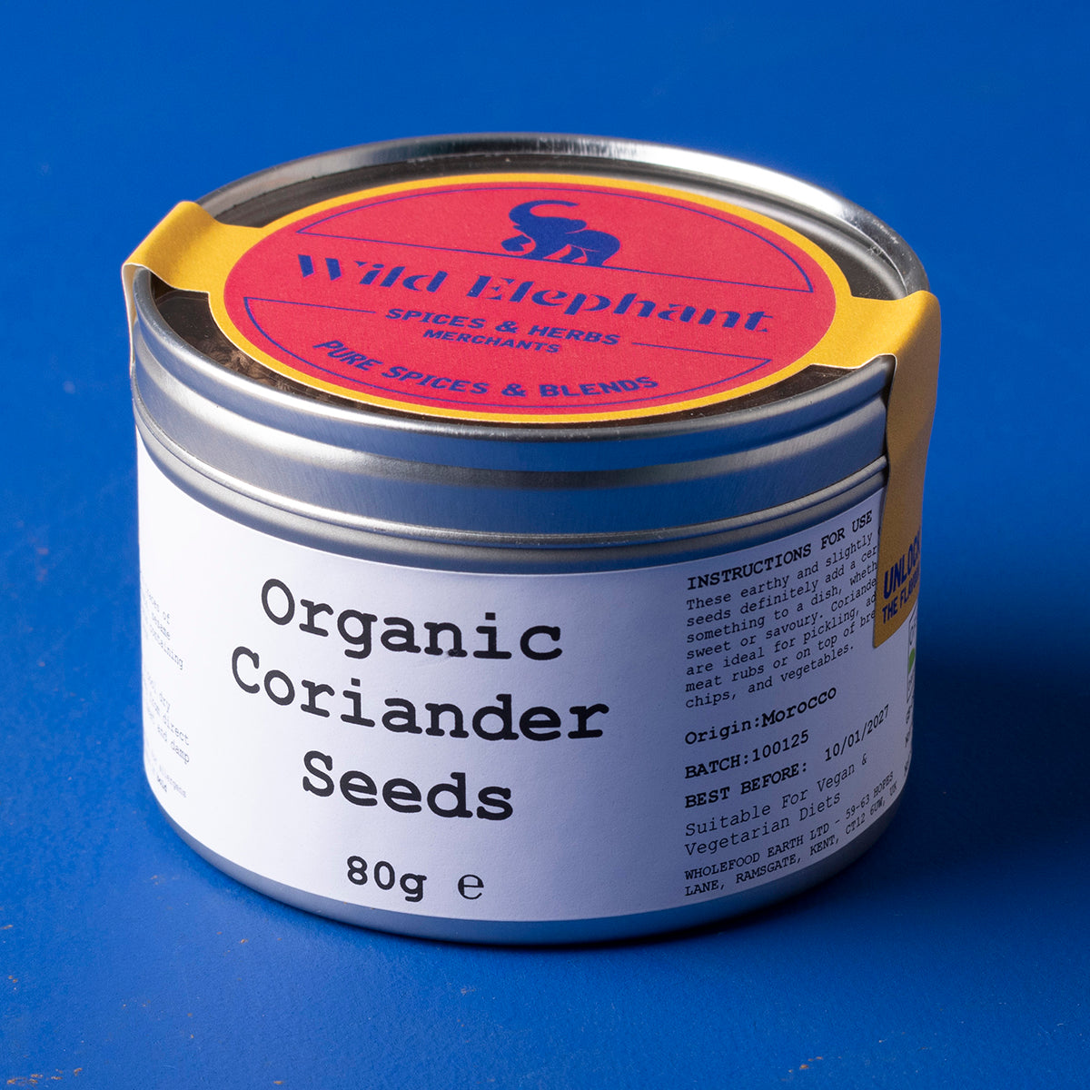 Organic coriander seeds from Wild Elephant, displayed in a clear jar, showcasing the small round, tan herbs used in cooking.