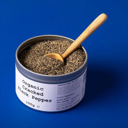 Organic cracked black pepper from Wild Elephant, Whole Food Earth Herbs & Spices, showing fresh, coarse black peppercorns in a jar.