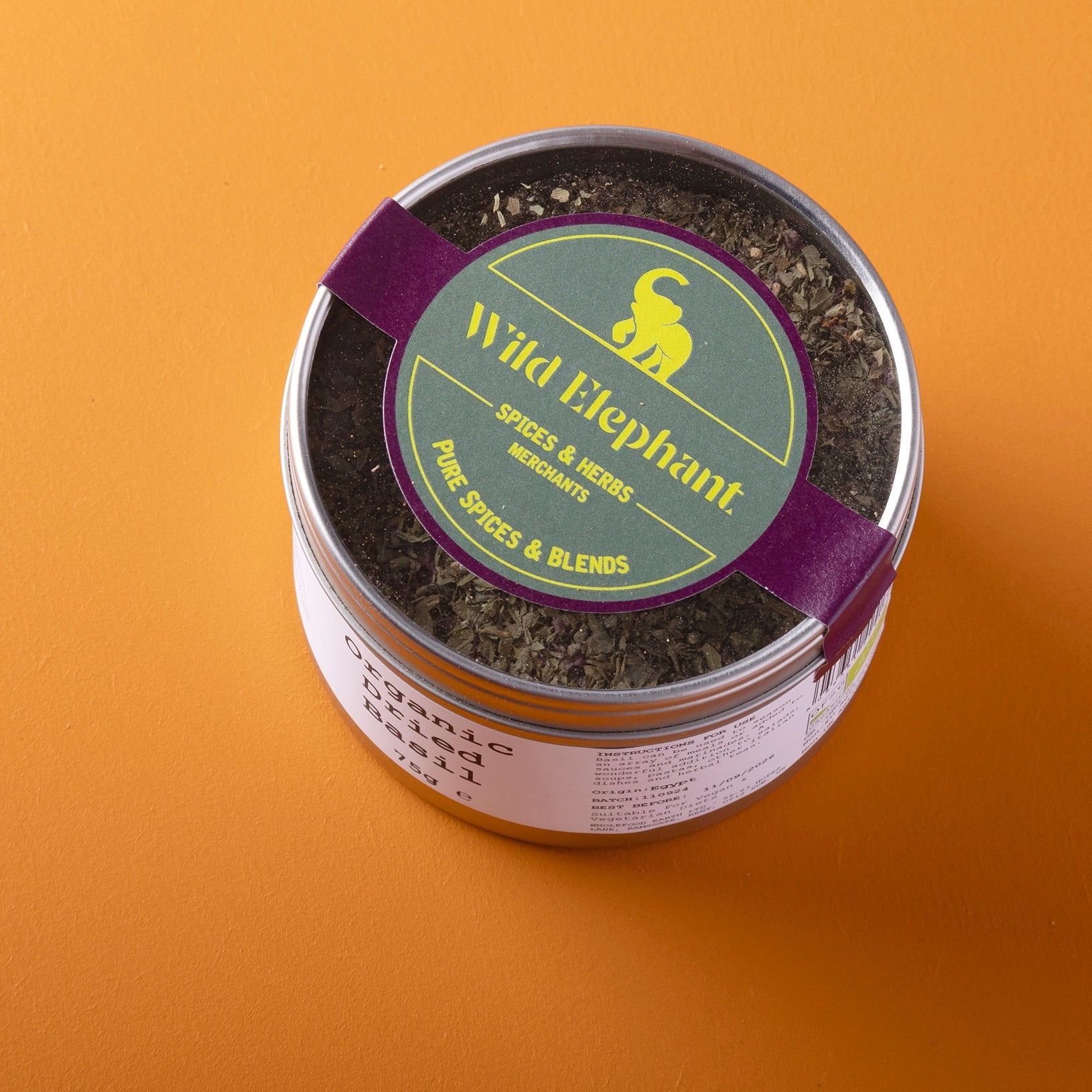 Organic dried basil from Whole Food Earth, shown in a 75g package, with fresh green basil leaves and herbs in a natural setting.