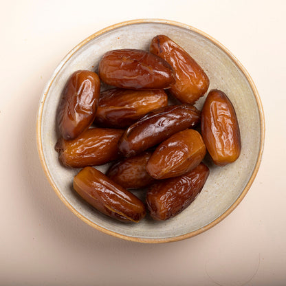 Pack of organic Deglet Nour dates with pits from Whole Food Earth, showing glossy, dried dates on a white background.