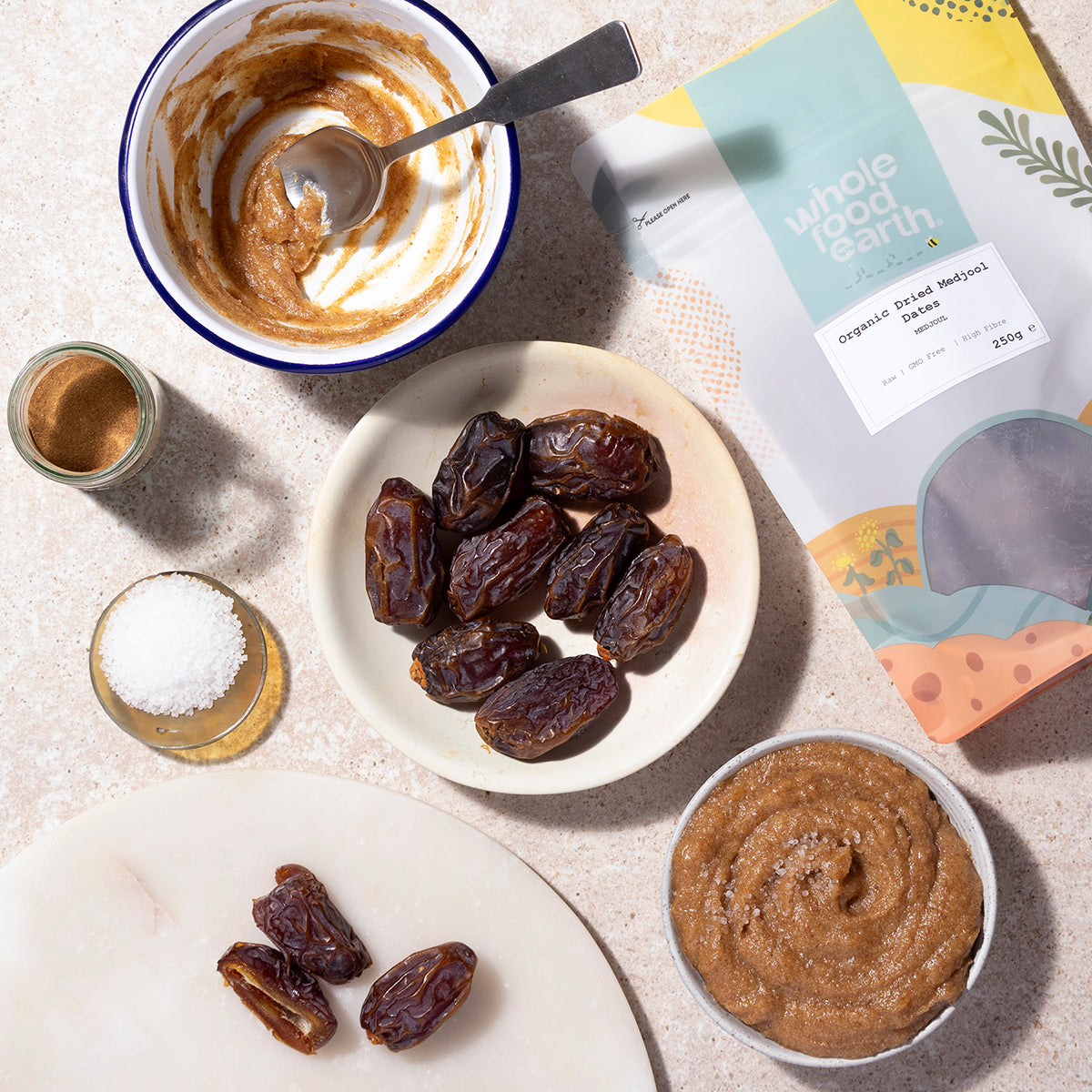 Organic dried Medjool dates from Whole Food Earth displayed in a bowl with some dates nearby on a wooden table.